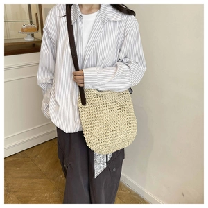 Detail of a beige woven tote bag with brown leather straps and decorative floral scarf