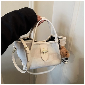Detail of cream women's tote bag with gold metal buckle and cute teddy bear pendant