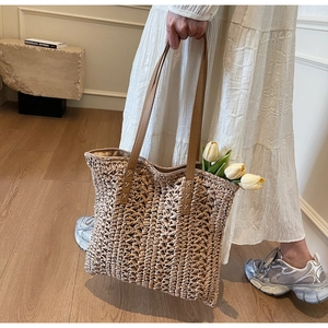 Close-up of hand-woven texture and brown leather handle with stitching on tote bag