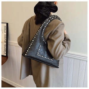Detail view of vintage black rivet shoulder bag on model showing size and texture