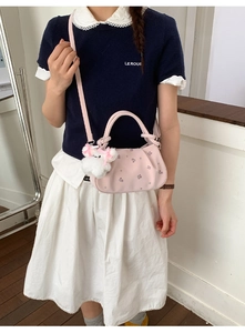 Detail of pink embroidered dumpling bag with floral patterns and a plush toy charm