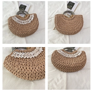 Détail du sac à main en paille tressée avec coquillages et poignées à rayures plage