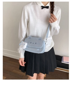 Detail of light blue cat-themed crossbody bag with cat ear design and plush pendant