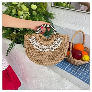 Détail d'un sac en paille avec décor en coquillages et poignée rayée pour tenue de plage