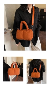 Detail of bright orange quilted nylon puffer bag with plush top handle and shoulder strap