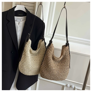 Detail of woven straw tote bags in beige and brown with adjustable leather shoulder straps