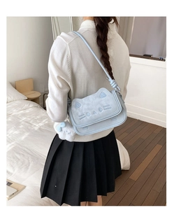 Close-up of light blue cat-shaped crossbody bag featuring cute embroidery and plush charm
