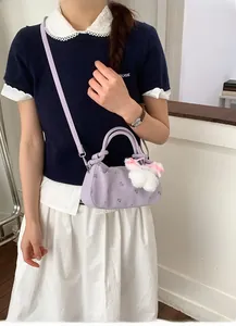 Detail view of purple floral dumpling bag with plush rabbit charm and shoulder strap