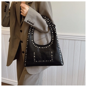 Close-up of black vintage underarm bag with silver rivets and textured leather finish