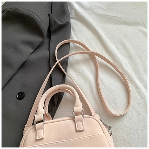 Détail du sac polochon en cuir rose avec poignées rondes et garnitures métalliques argent
