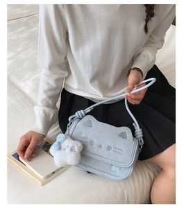 Detail of light blue cat-shaped crossbody bag featuring cute embroidery and plush charm