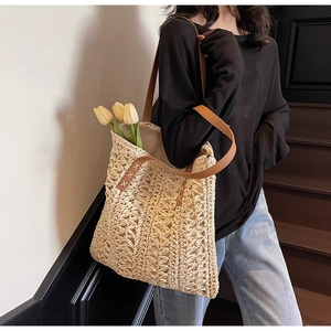 Detail of hand-woven beige tote bag with brown leather straps and intricate stitch work