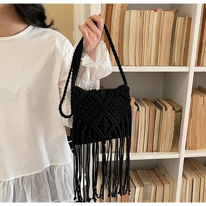 Detalle del bolso de hombro de macramé negro con flecos y patrón tejido bohemio