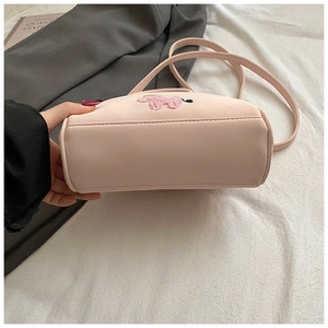 Détail d'un sac en cuir PU rose texturé avec patch caniche en peluche et fermeture éclair