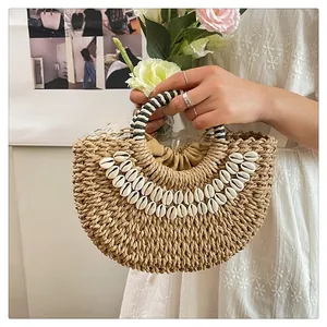 Détail du sac à main en paille avec ornements en coquillages et poignée rayée