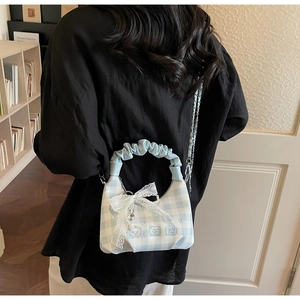 Detail of light blue gingham crossbody bag with ruffle handle and lace bow decoration