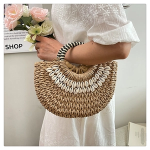 Détail du sac à main bohème en paille avec coquillages blancs et anses tissées
