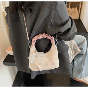 Detail of beige pleated handbag with cute bear embroidery and pink silk handle