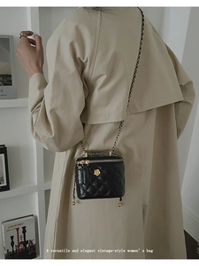 Detail of black quilted box bag featuring a gold camellia ornament and chain strap
