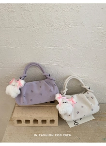 Detail of floral embroidery and pleats on chic dumpling bags with cute plush charms