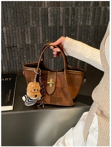 Detailed shot of brown textured tote bag featuring a cute puppy pendant and gold lock