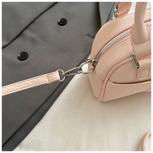 Détail du sac Boston rose montrant le zip argenté et la bandoulière amovible
