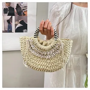 Détail du sac en paille avec ornements en coquillages blancs et anses rayées