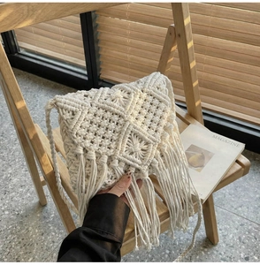 Detalle de bolso bohemio de ganchillo blanco con flecos largos en una silla de madera