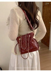 Macro view of burgundy quilted leather bucket bag with elegant golden chain handles