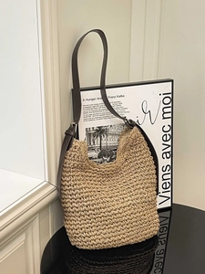 Minimalist woven straw tote bag with brown leather shoulder strap for beach vacation style