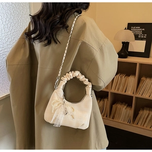Detailed view of cream corduroy crescent bag with lace bow and metal chain strap