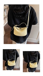 Close-up of a pale yellow crescent leather bag featuring a polished metal twist lock