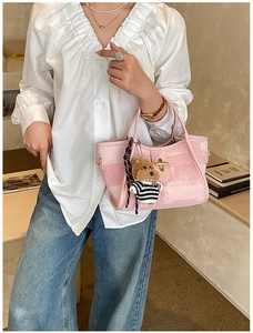 Pink textured tote bag with metal lock and cute teddy bear charm on white shirt model