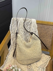 Chic woven straw tote bag with brown leather straps on a vintage chair for beach vacation