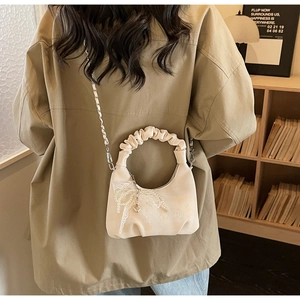 Detail of cream pleated cloud handle handbag with pearl lace bow and silver chain strap