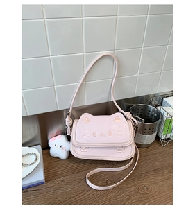 Close-up of pink kitty crossbody bag with cat face embroidery and plush mascot charm