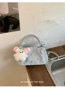Detail of light blue floral handbag with white plush bunny charm and pleated leather design