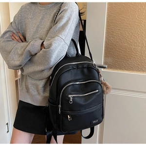 Close-up of black pebble leather backpack with silver zippers and plush charm detail