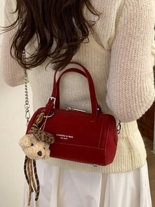 Sac bowling rouge avec chaîne et breloque ours porté par un mannequin en tenue blanche