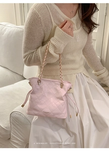 Close-up of pink quilted bucket bag with gold chain strap and drawstring closure