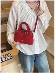Détail du sac à main rouge avec écusson brodé de chien et doubles poignées rondes