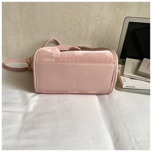 Detail of pink bucket bag featuring stitched leather base and metal strap attachments