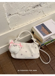Detail of white floral dumpling bag featuring a plush bunny charm and pleated texture