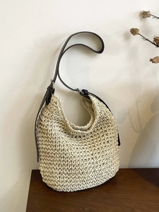 Minimalist woven straw tote bag with brown leather strap for beach vacations