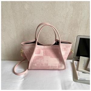 Detail of light pink geometric print tote bag with laptop and books in a modern setting