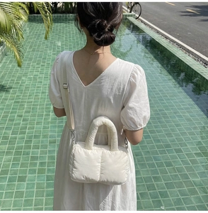 Detailed view of a white quilted puffer shoulder bag with detachable strap on a model