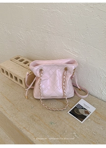 Close-up of light pink quilted bucket bag with gold chain strap and luxury leather texture