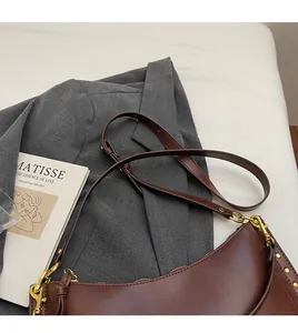 Detail of vintage brown matte leather crescent bag with gold hardware and adjustable strap