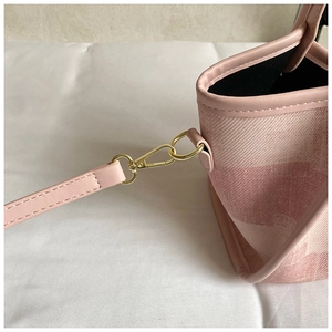 Detailed shot of pink textured handbag showing gold metal hooks and detachable strap