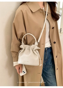 Sac seau plissé blanc crème avec cordon de serrage porté avec un trench-coat kaki